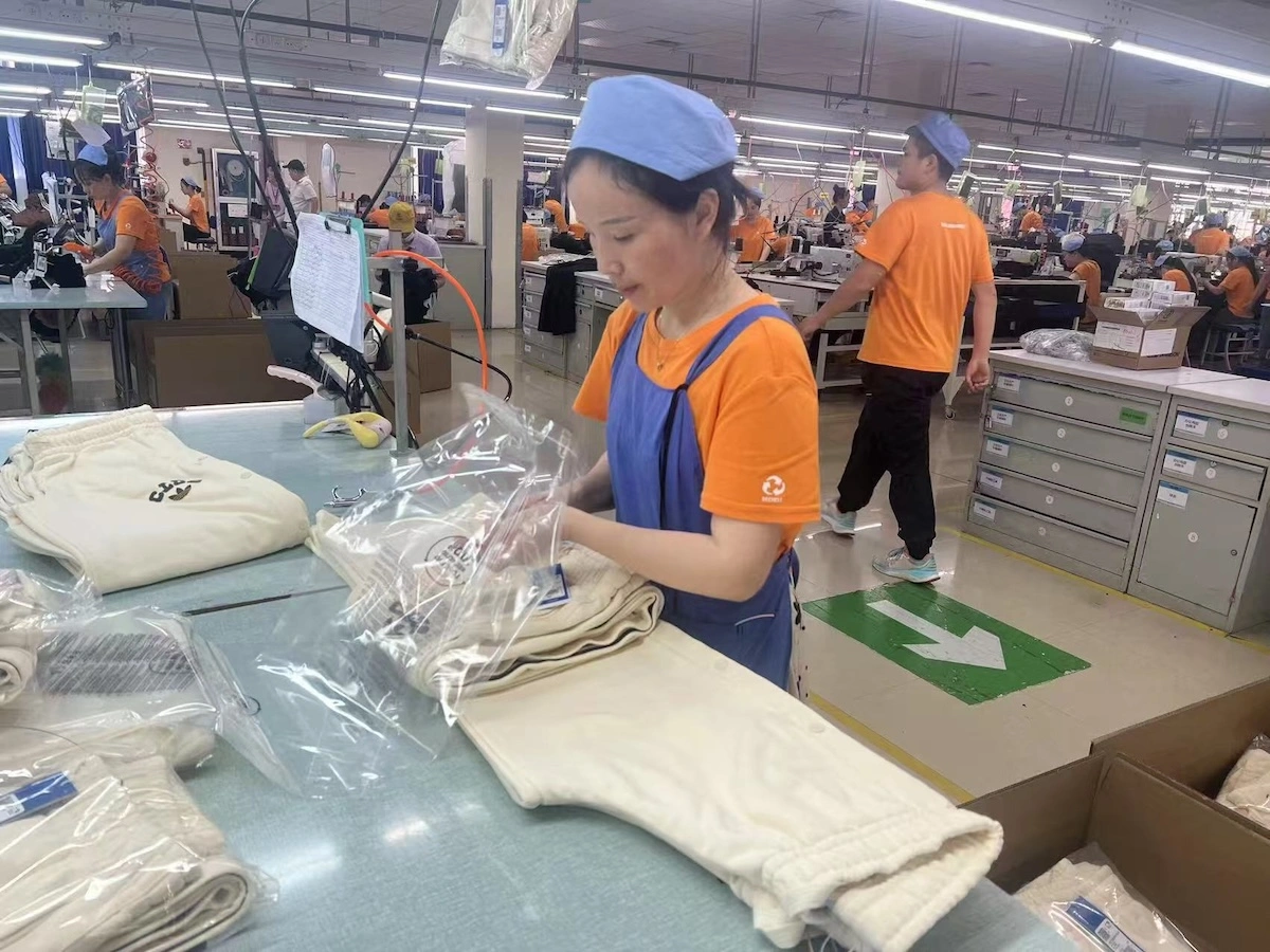 A worker packing folded garments into a polybag