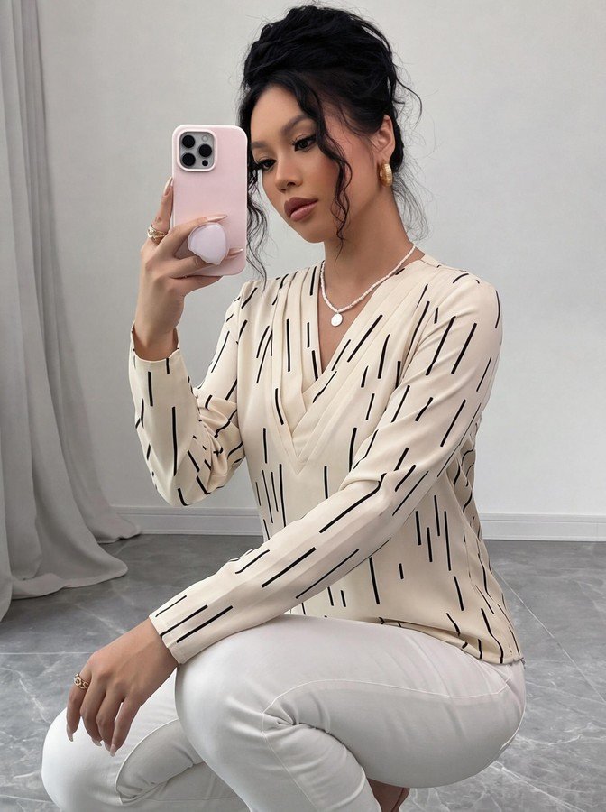 Seated front view of the ivory abstract-dash print v-neck long-sleeve blouse, showing the silhouette and fit.