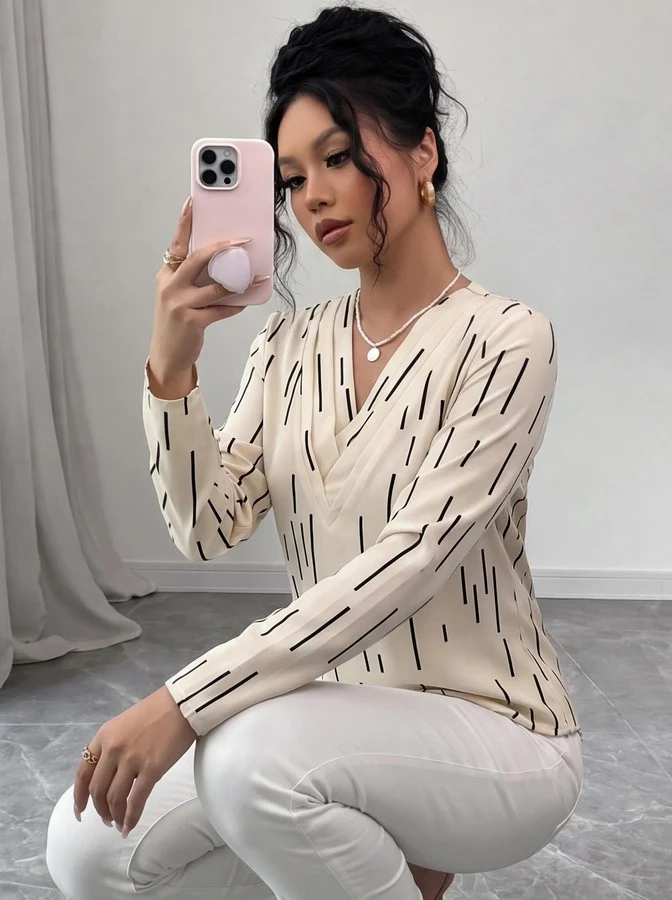 Seated front view of the ivory abstract-dash print v-neck long-sleeve blouse, showing the silhouette and fit.