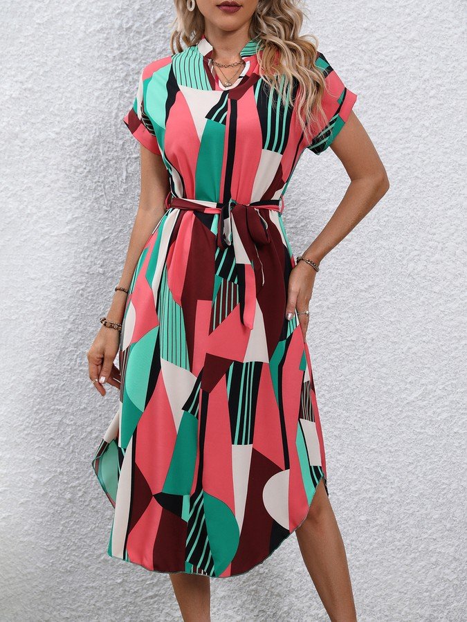 Angled front view of the pink and green abstract geometric shirt dress, showing its silhouette and design details.