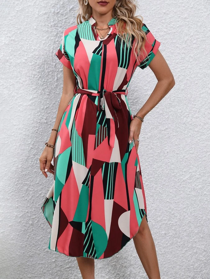 Angled front view of the pink and green abstract geometric shirt dress, showing its silhouette and design details.