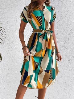 Front view of the teal and yellow abstract geometric shirt dress, showing its silhouette and design details.
