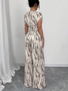 Back view of the cream and black striped one-shoulder jumpsuit, showing its silhouette and design details.