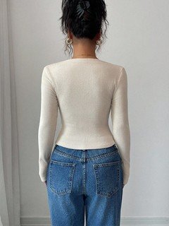Back view of the ivory asymmetric draped-neck top, showing its silhouette and design details.