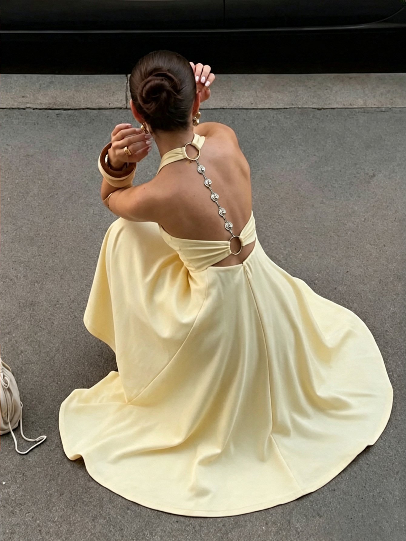 A backless cross-strap maxi dress photographed with the wearer seated A backless cross-strap maxi dress photographed with the wearer seated