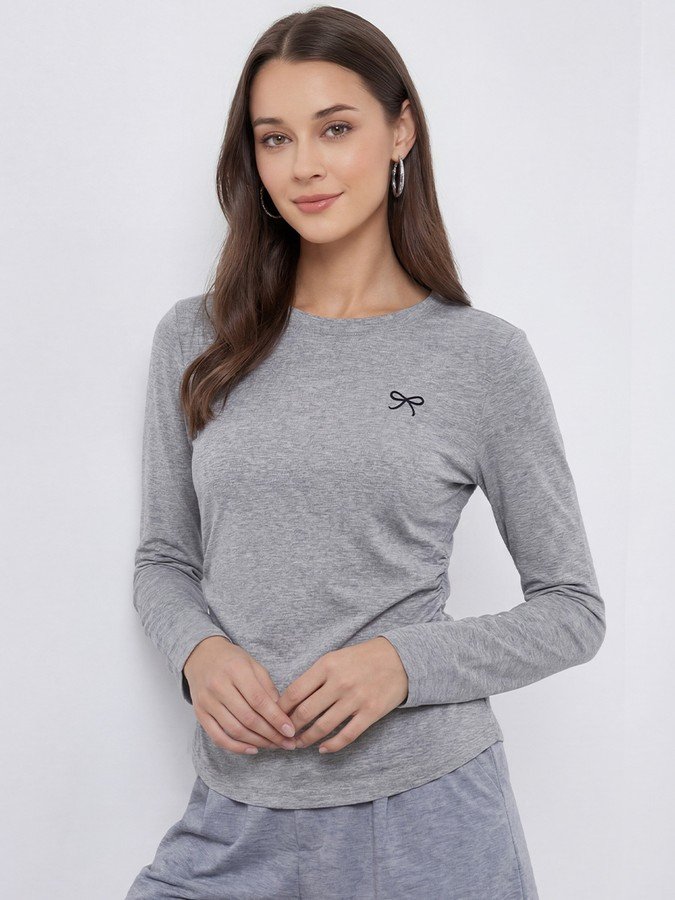 Angled front view of the gray bow-motif long-sleeve ruched top, showing its silhouette and design details.