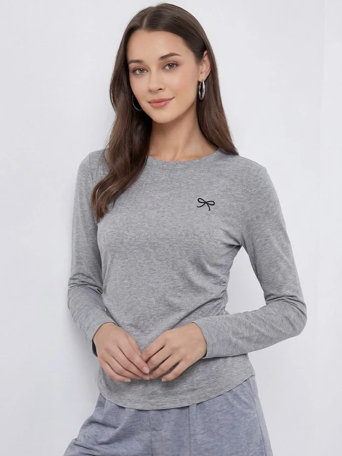 Angled front view of the gray bow-motif long-sleeve ruched top, showing its silhouette and design details.