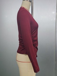 Mannequin view of the burgundy bow-motif long-sleeve ruched top, showing the garment shape and construction.