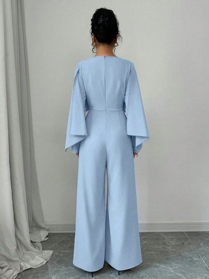 Back view of the light blue cape-overlay tie-waist wide-leg jumpsuit, showing the silhouette and fit.