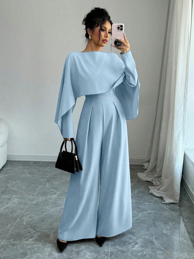 Front view of the light blue cape-overlay tie-waist wide-leg jumpsuit, showing the silhouette and fit.