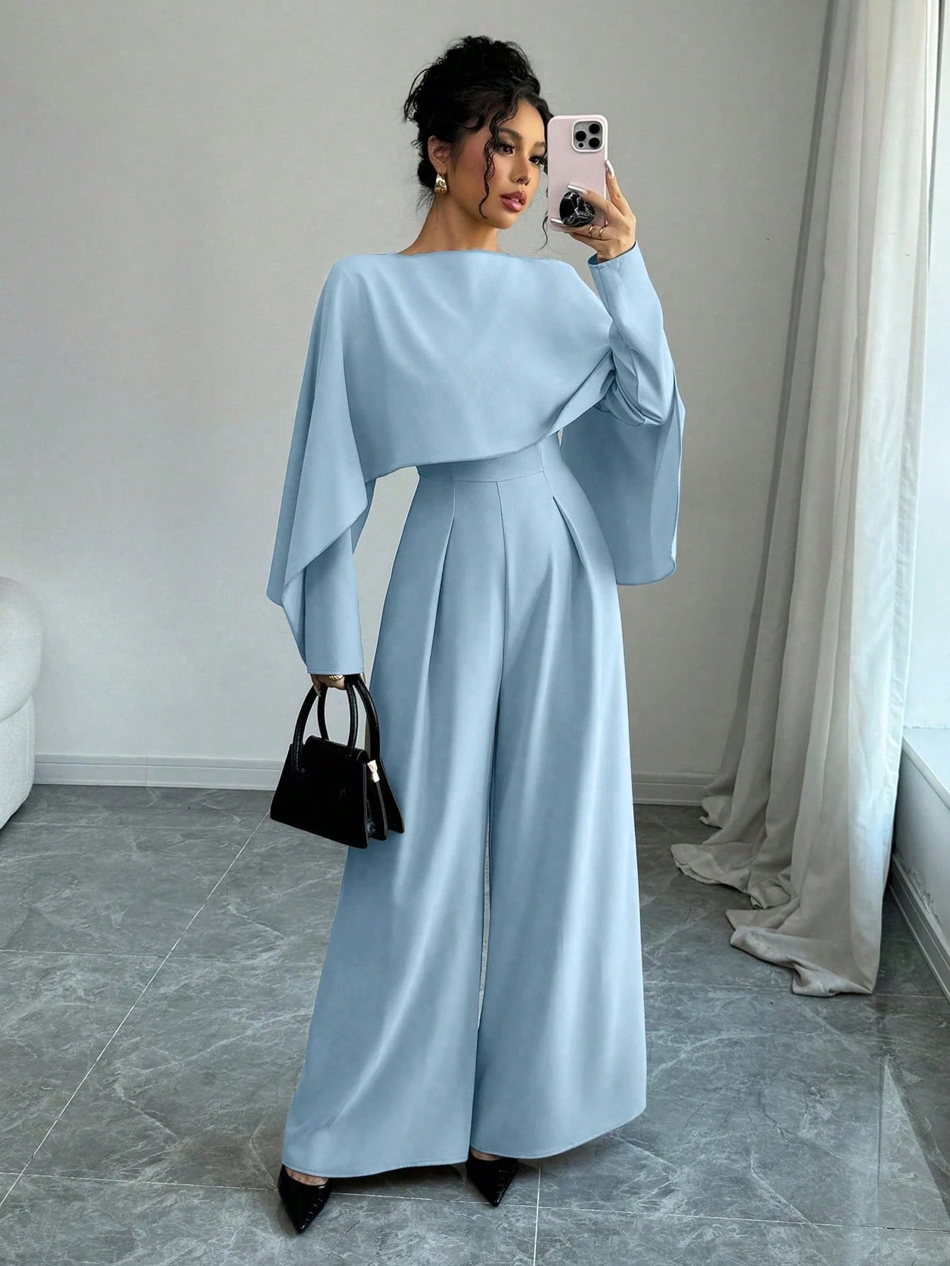 Front view of the light blue cape-overlay tie-waist wide-leg jumpsuit, showing the silhouette and fit.