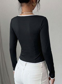 Back view of the black contrast-piping tie-front long-sleeve top, showing the silhouette and fit.