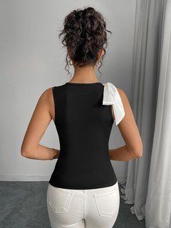 Angled back view of the black and white shoulder-bow sleeveless top, showing its silhouette and design details.