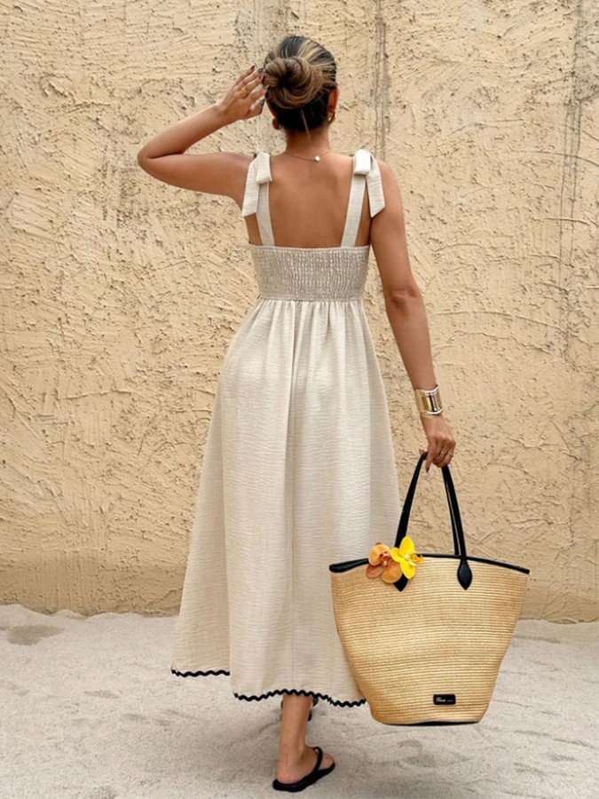 Back view of the cream and black contrast-trim tie-strap maxi dress, showing its silhouette and design details.