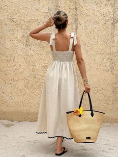 Angled back view of the cream and black contrast-trim tie-strap maxi dress, showing its silhouette and design details.