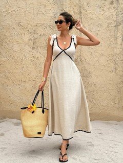 Angled front view of the cream and black contrast-trim tie-strap maxi dress, showing its silhouette and design details.
