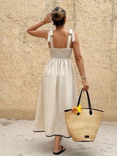 Back view of the cream and black contrast-trim tie-strap maxi dress, showing its silhouette and design details.