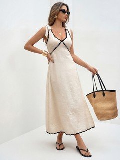 Lifestyle front view of the cream and black contrast-trim tie-strap maxi dress, showing its silhouette and design details.