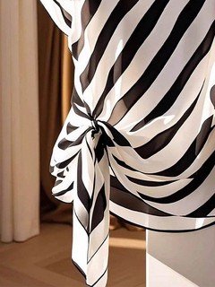 Construction detail of the black and cream diagonal stripe side-tie blouse, showing the garment finish.