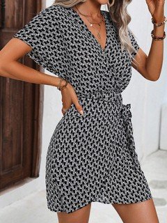 Full-length front view of the black and white ditsy print tie-waist wrap dress, showing its silhouette and design details.