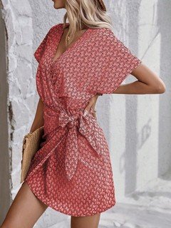 Full-length front view of the coral ditsy print tie-waist wrap dress, showing its silhouette and design details.