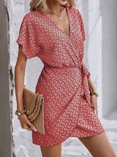 Styled front view of the coral ditsy print tie-waist wrap dress, showing its silhouette and design details.