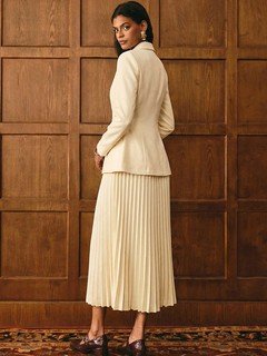 Angled back view of the cream blazer and pleated midi skirt set, showing its silhouette and design details.