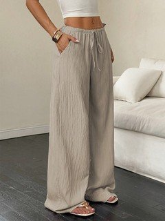 Lifestyle front view of the beige drawstring wide-leg pants, showing its silhouette and design details.
