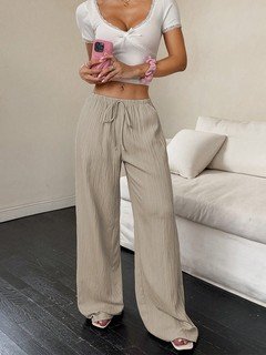 Three-quarter front view of the beige drawstring wide-leg pants, showing its silhouette and design details.
