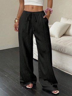 Angled front view of the black drawstring wide-leg pants, showing its silhouette and design details.