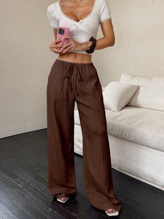 Angled front view of the brown drawstring wide-leg pants, showing its silhouette and design details.