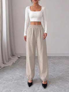 Full length front view of the beige drawstring-waist tapered jogger pants, showing the silhouette and fit.