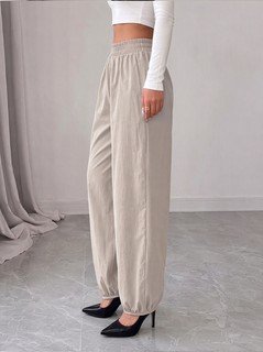 Side view of the beige drawstring-waist tapered jogger pants, showing the silhouette and fit.