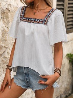 Angled front view of the white embroidered square-neck blouse, showing its silhouette and design details.