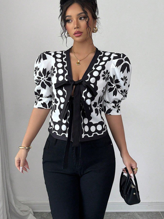 Front view of the black and white floral puff-sleeve tie-front top, showing its silhouette and design details.