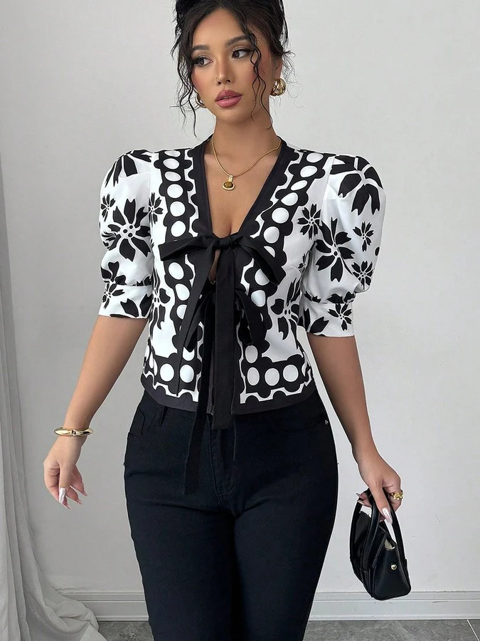 Front view of the black and white floral puff-sleeve tie-front top, showing its silhouette and design details.