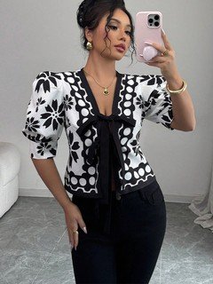 Angled front view of the black and white floral puff-sleeve tie-front top, showing its silhouette and design details.