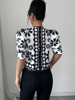 Back view of the black and white floral puff-sleeve tie-front top, showing its silhouette and design details.