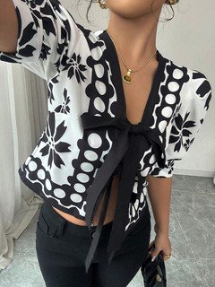 Close-up of the black and white floral puff-sleeve tie-front top, showing its silhouette and design details.