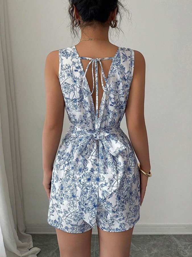 Back view of the blue and white floral square-neck tie-back romper, showing its silhouette and design details.