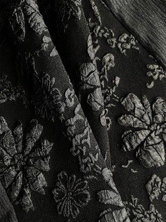 Fabric detail of the black floral textured square-neck dress, showing the surface texture and finish.