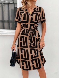 Angled front view of the black and tan geometric belted shirt dress, showing its silhouette and design details.