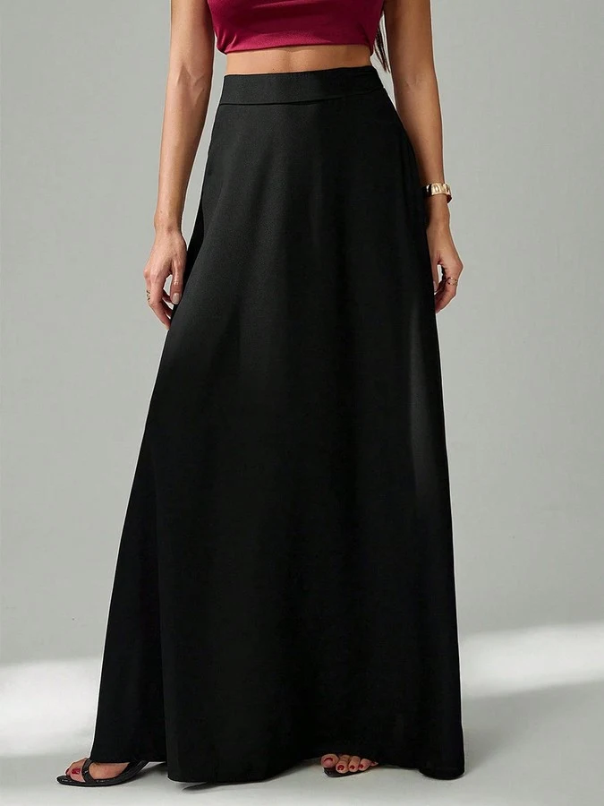 Angled front view of the black pleated a-line maxi skirt, showing its silhouette and design details.