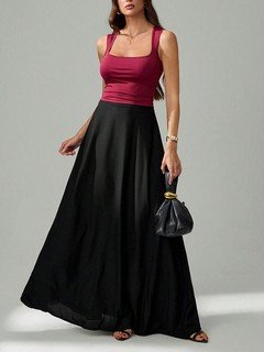 Three-quarter front view of the black pleated a-line maxi skirt, showing its silhouette and design details.