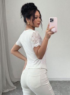 Side view of the white lace-sleeve crew-neck short-sleeve top, showing the silhouette and fit.