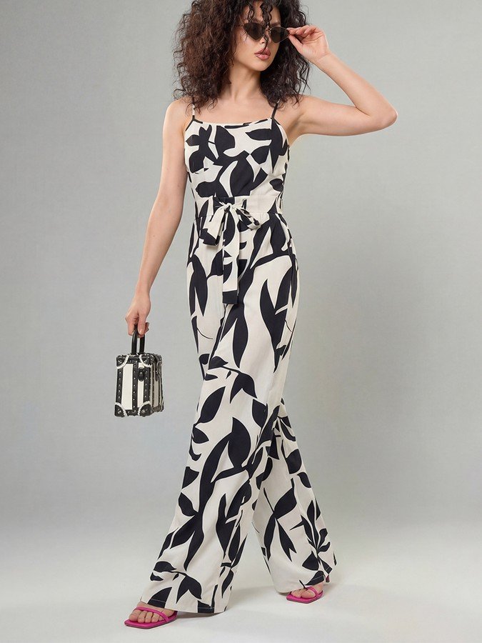 Angled front view of the black and white leaf print wide-leg jumpsuit, showing its silhouette and design details.
