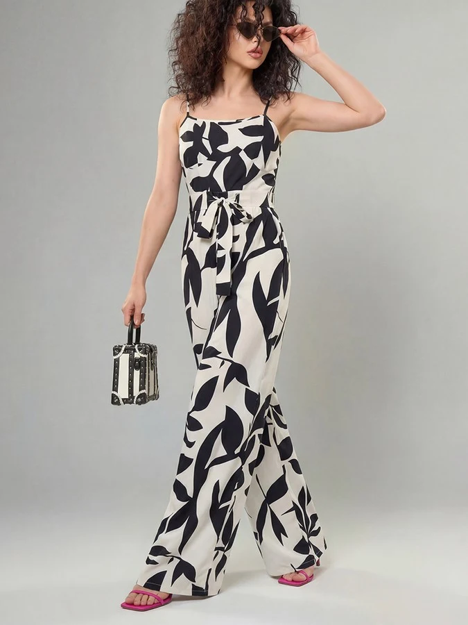 Angled front view of the black and white leaf print wide-leg jumpsuit, showing its silhouette and design details.