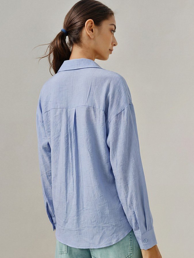 Back view of the blue collared side-tie wrap shirt, showing its silhouette and design details.