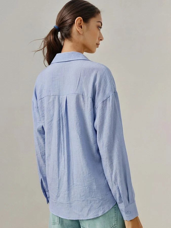 Back view of the blue collared side-tie wrap shirt, showing its silhouette and design details.