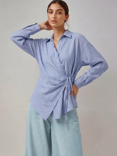 Angled front view of the blue collared side-tie wrap shirt, showing its silhouette and design details.